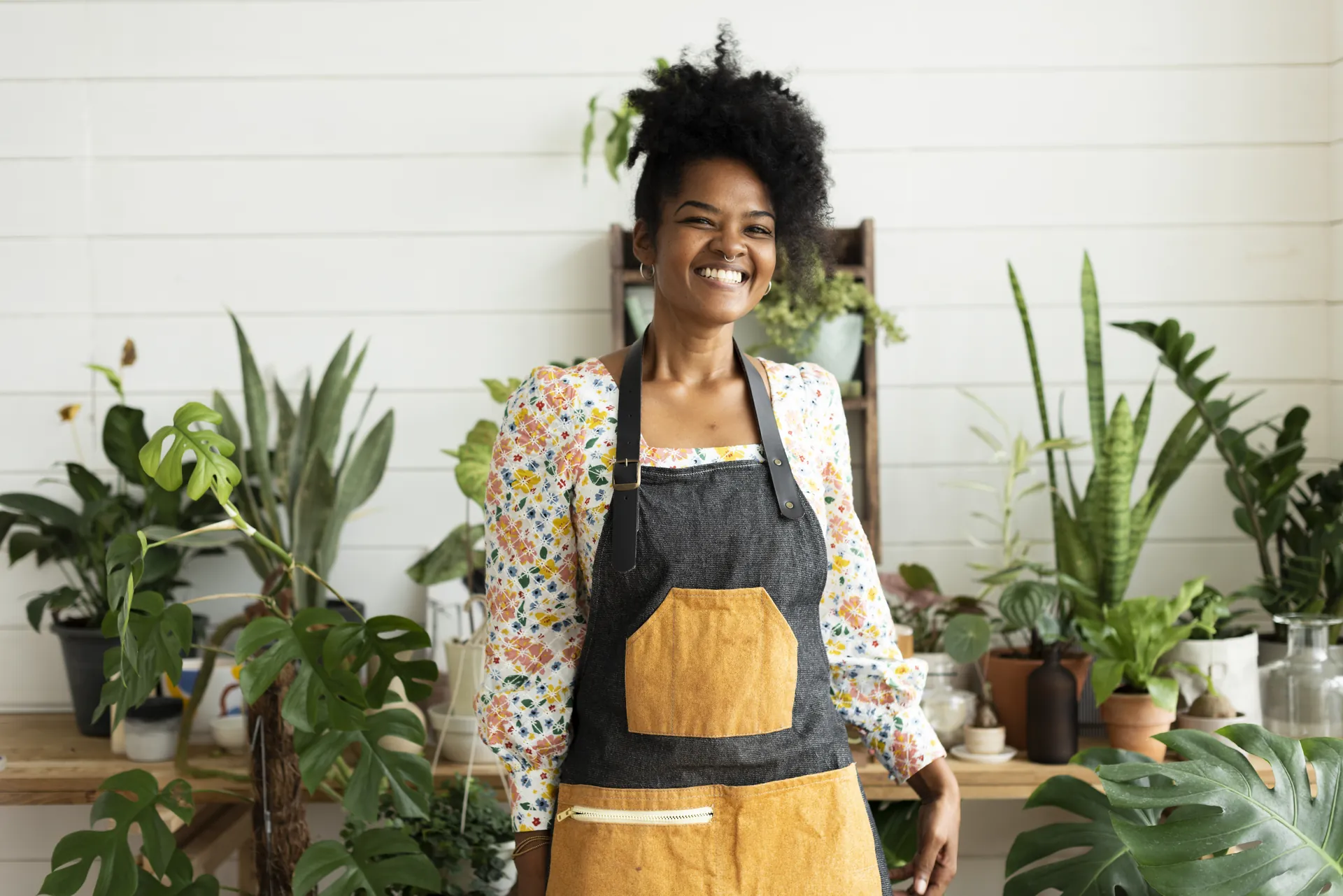 Smiling small-business owner in an apron in her plant shop