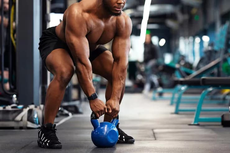Athlete lifting a kettlebell from the floor in a modern gym