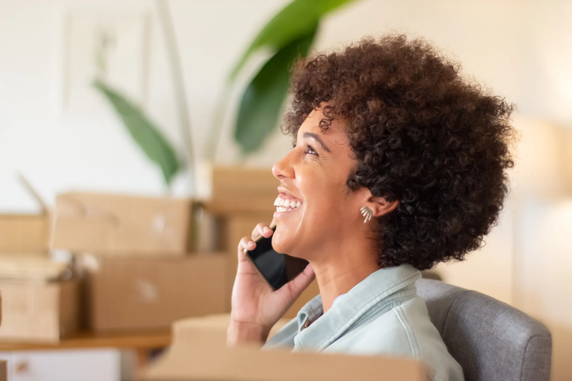 Smiling online-shop owner on a phone call, surrounded by parcels ready to ship