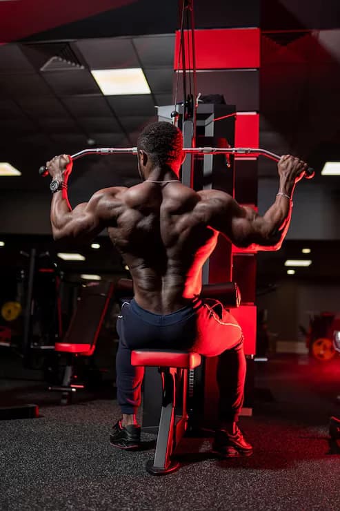 Athlete training on a lat pulldown machine in a gym, seen from behind